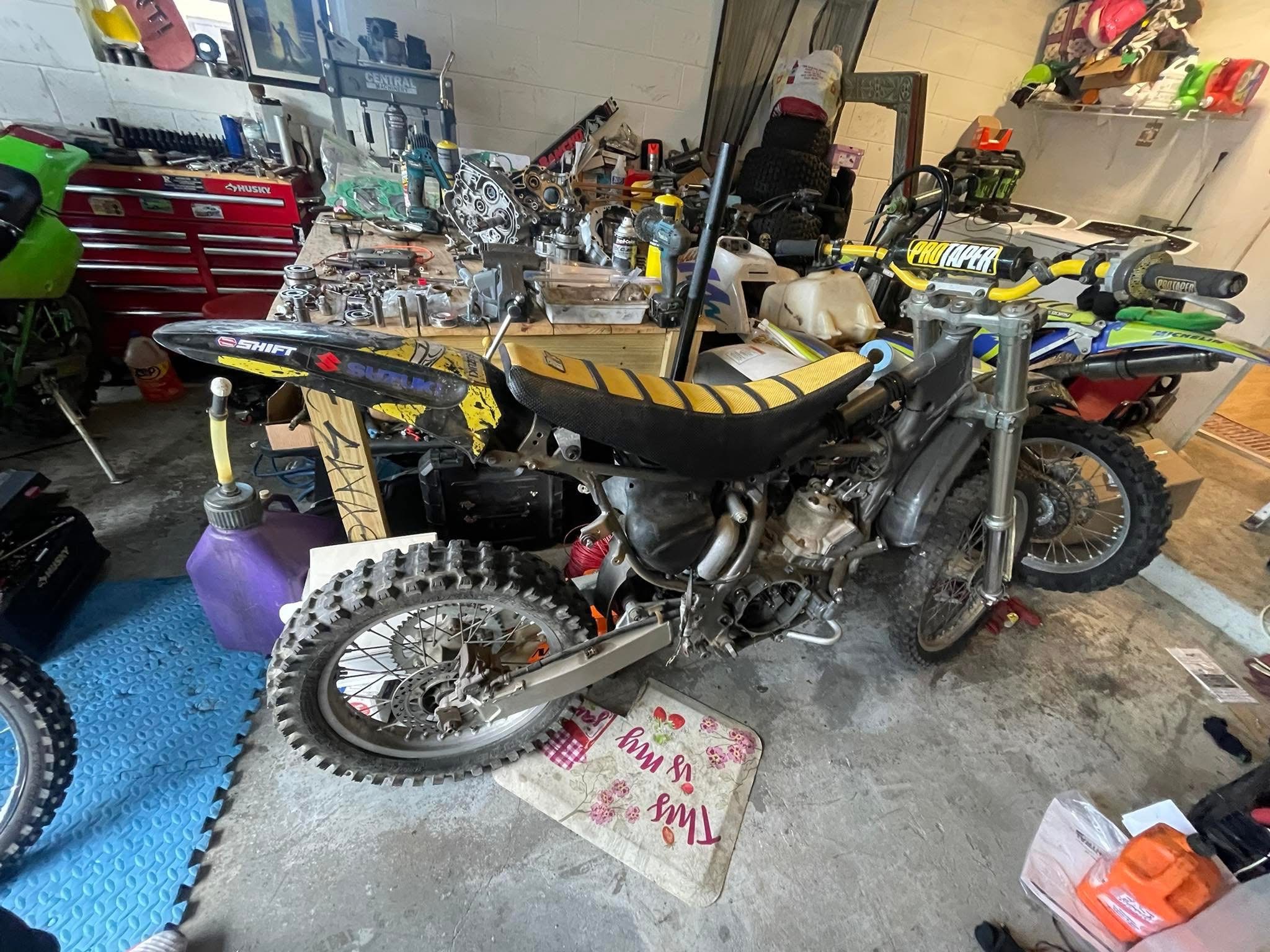 Dirt bike engine components and a used off-road motorcycle in a working workshop